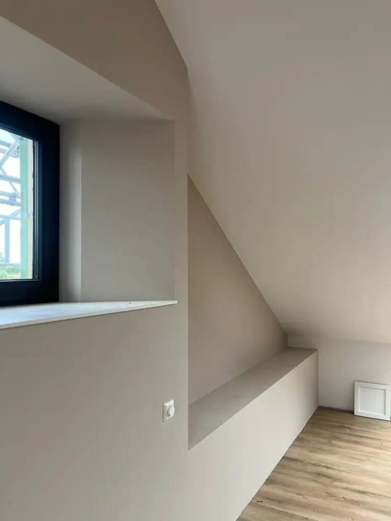 Strak afgewerkte nieuwbouwwand met hoog plafond en raamnis