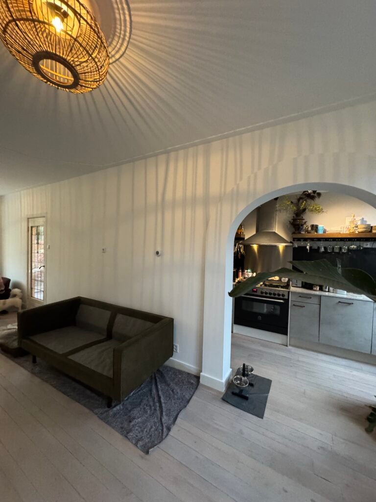 Afgewerkte woonkamer met strak stucwerk rond een boog en plafond
