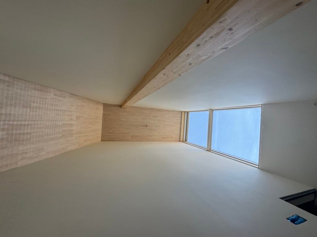 Grote ruimte met gladde wand en plafond naast een houten draagbalk