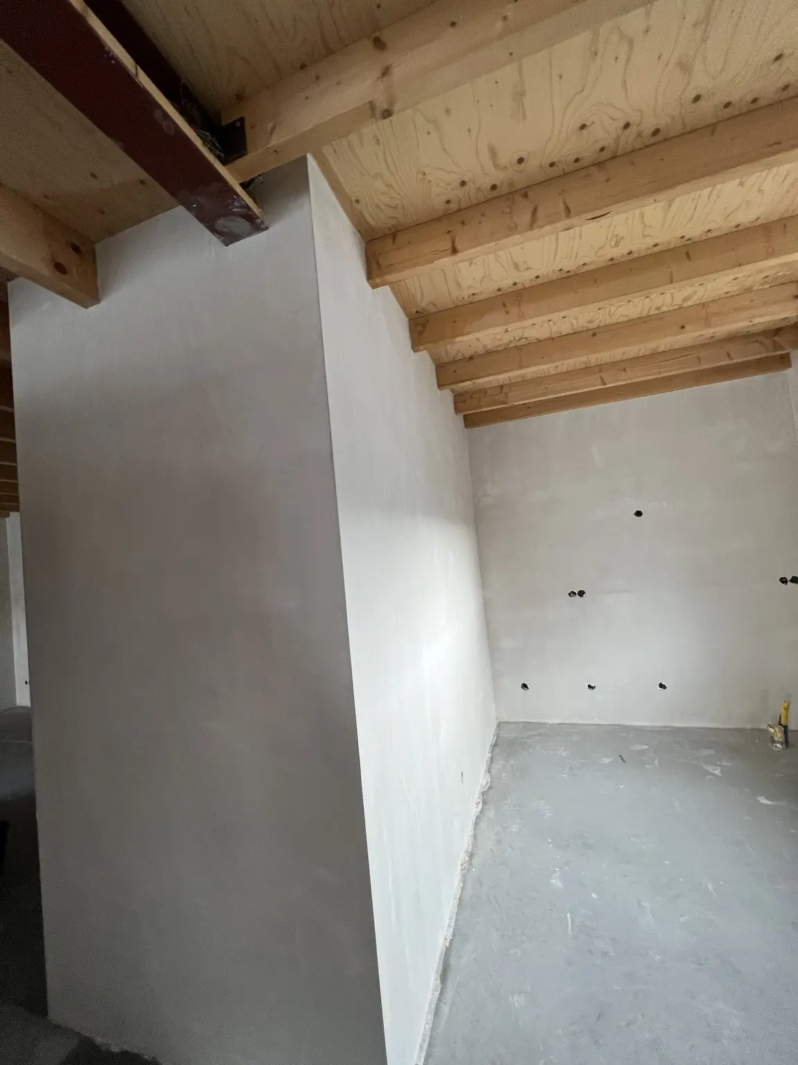 Witte wandvlakken onder een houten balkenplafond